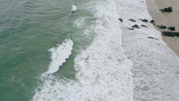波が激しいスコットランドの砂浜の遅い動きの空中は 潮に巻き込まれているサーファーがビーチに向かって洗い流されています — ストック動画