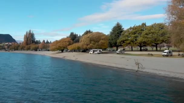 去年秋天 在新西兰瓦纳卡湖美丽的蓝色湖畔的海滩上 空中无人机飞向一辆野营车 — 图库视频影像