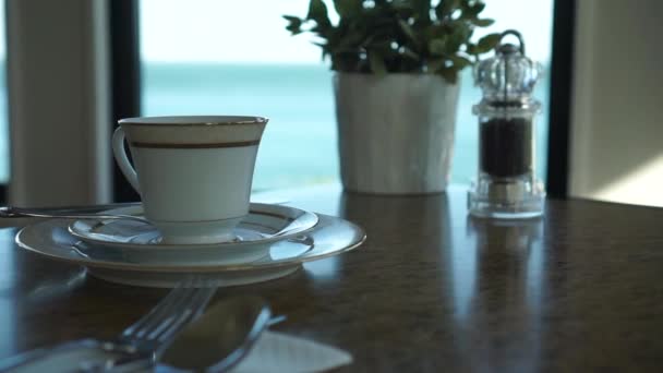 Slowmo オーシャンビューの高級ブティックホテルの朝食テーブルでコーヒーの古い磁器カップ Close — ストック動画