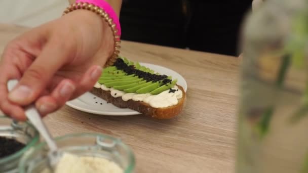 Slowmo Förbereda Avokado Rostat Bröd Med Svartvita Sesamfrön Och Hummus — Stockvideo