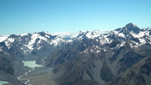 Slowmo 飛行機の風光明媚なフライトからニュージーランドの南アルプス アオラキ山クック国立公園で雪をかぶった岩場の山々とゴドリー川渓谷氷河湖 — ストック動画