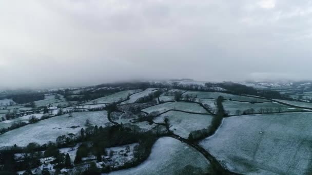 手付かずの雪と霜の多い田舎の環境を横断する空中追跡 緑と白の英語のフィールド 霧と霧が突然視界から丘を切り取った — ストック動画