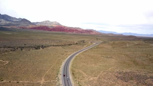 カメラがネバダ州のレッドロックキャニオンの赤い岩に向かって押すと 前方に移動する車と高速道路の空中 — ストック動画