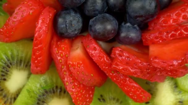 フルーツサラダの中心 円形のパターンで提示されたさまざまな果物の服を着たプレートの回転ショット — ストック動画