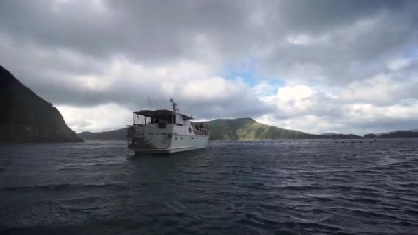 Cruiseboot Met Mensen Vissen Verankerd Baai Met Heuvel Achter Nieuw — Stockvideo