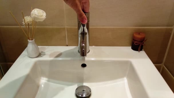 宾馆房间里从豪华浴室的白色水池中流出的水 不锈钢 不锈钢 湿透了冷水和热水 — 图库视频影像