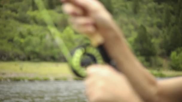 スローモーションフライフィッシング中にウェーダーを身に着けている男性漁師のショット 彼は釣った魚を釣ろうとしている ユタ州のプロボ川の真ん中に立っている — ストック動画