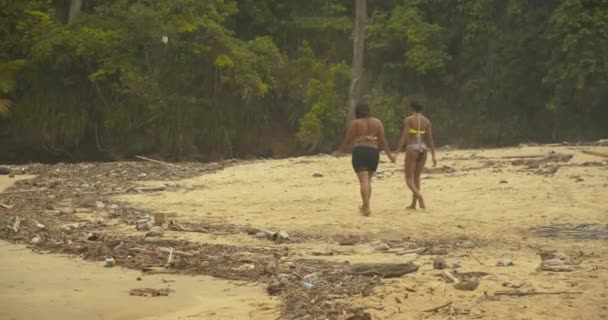 二人の女の子が手を取り合ってビーチを歩く — ストック動画