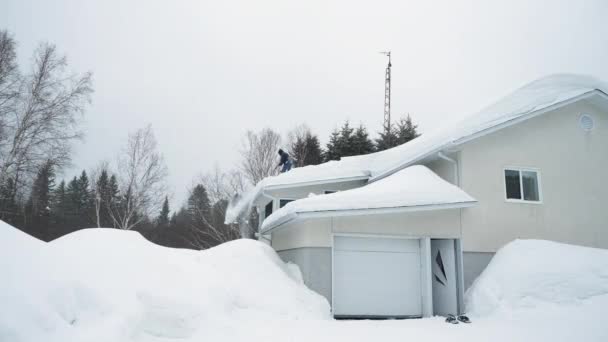嵐の後家の屋根から雪を押す男 — ストック動画