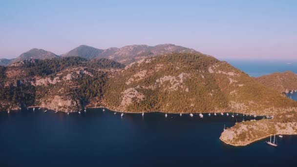 空中的无人驾驶飞机驾驶着帆船和游艇在地中海的海湾泻湖上空飞行 金光闪闪的天际带着奇异的蓝色色彩的水 土耳其靠近希腊 欧洲的热带太阳日 — 图库视频影像