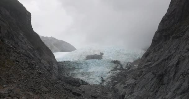 灰色の岩に囲まれたニュージーランドの凍ったロブ ロイ氷河の上昇ショットは 曇り空の日に 上に移動します — ストック動画