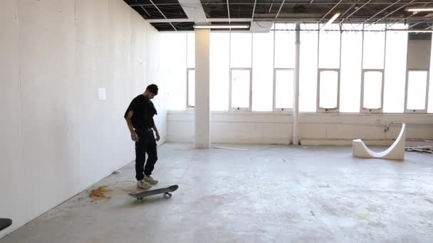 放棄された工場で彼のスケートボードで遊んで若い男のスローモーションと彼の携帯電話をチェック — ストック動画