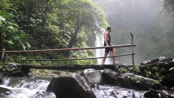 Young Fit White Man Crossing Handmade Bamboo Bridge Goes River — Stock Video