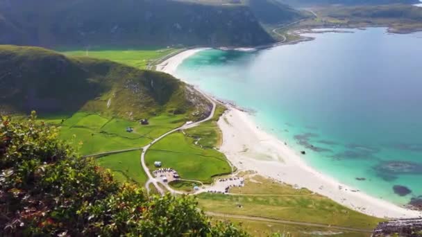 在一个阳光明媚的夏日 从位于挪威Lofoten的Haukland海滩上方的Mannen山眺望 蓝绿色和蓝色的海洋与背景为峡湾的白色沙滩相交 — 图库视频影像