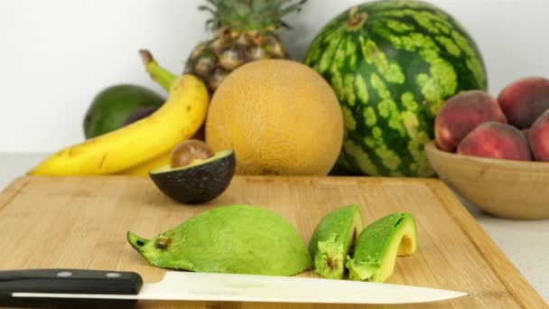 在切菜板上的一些切片鳄梨的跟踪镜头 在各种水果碎片和一个简单的白色背景前 — 图库视频影像
