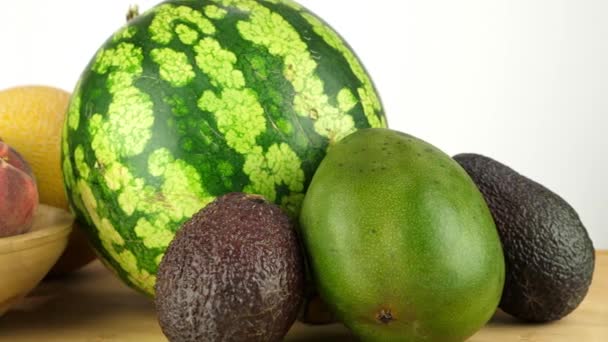 白い背景を背景にまな板に新鮮な果物の混合物のスライダーショット スイカ マンゴー アボカド メロン — ストック動画