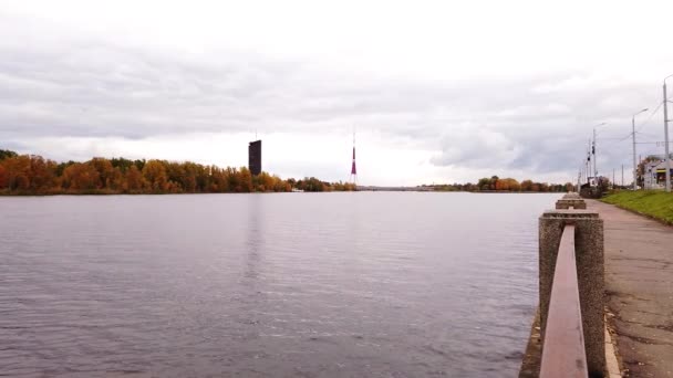 在多云的秋日 里加电视塔在多古瓦河岸平静静谧的水中矗立 — 图库视频影像