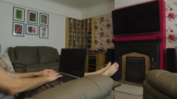 男士们靠在客厅的笔记本电脑上 从家里的广角镜头开始打字 — 图库视频影像