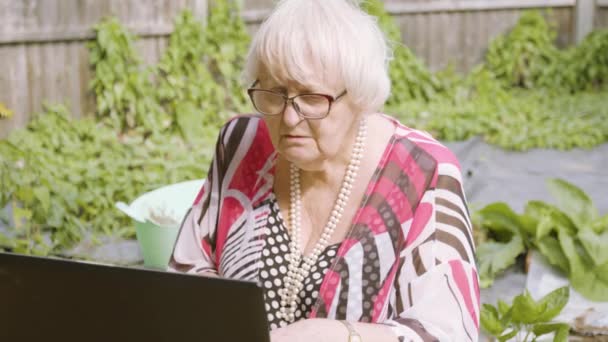 Yaşlı Kadın Bahçede Siyah Bir Dizüstü Bilgisayarla Çalışıyor — Stok video