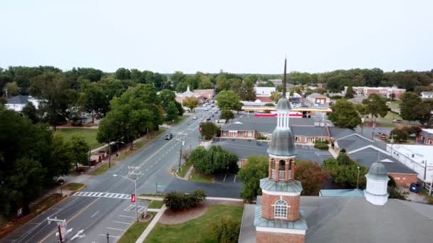 空中マシューズNc 4Kの背景に最初のバプテスト教会の尖塔を持つマシューズノースカロライナ州 — ストック動画