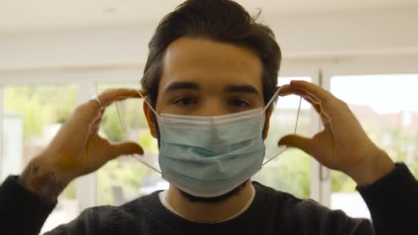 Mężczyzna Patrząc Prosto Aparat Zakładając Maskę Twarzy — Wideo stockowe