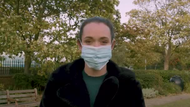 Frau Trägt Eine Mediale Gesichtsmaske Während Sie Die Kamera Blickt — Stockvideo