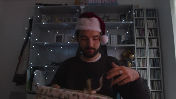 Άντρας Που Μιλάει Στο Βίντεο Ανοίγει Χριστουγεννιάτικο Δώρο Φορώντας Χριστουγεννιάτικο — Αρχείο Βίντεο