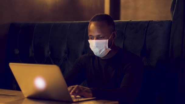 Man Typen Een Laptop Een Donkere Caf Met Een Gezichtsmasker — Stockvideo