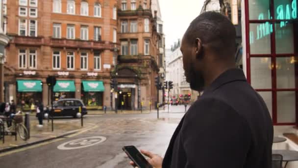 Hombre Negro Usando Teléfono Inteligente Una Calle Concurrida Londres — Vídeo de stock