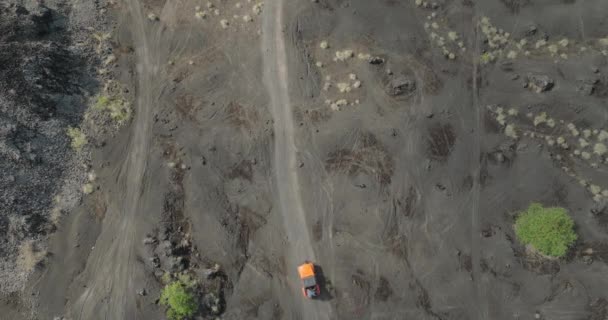 玄武岩砂のパス上のオレンジジープの運転 古い溶岩フィールド上の道路から4 トップダウン — ストック動画