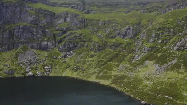 アイルランドのウォーターフォードにあるクムシニョーン ドローンは湖を越えて崖の方へ飛ぶ 湖は山に囲まれている 旅行とハイキングのコンセプト — ストック動画