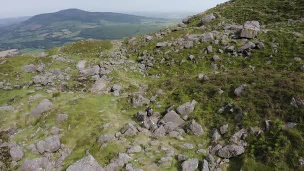 ドローンは山のハイキングコースでハイカーの上に乗ります アイルランドのウォーターフォードにあるクムシニョーン 旅行とハイキングのコンセプト — ストック動画