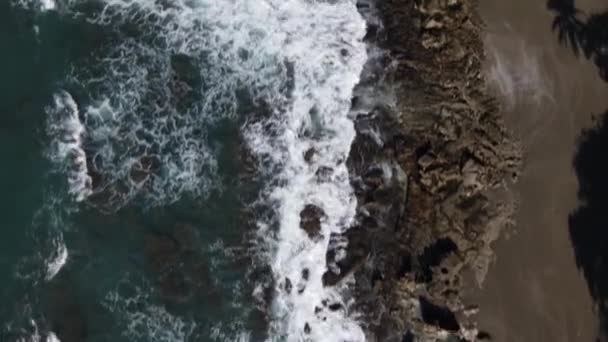 空中的波浪在黑暗的沙滩上拍打着岩石 — 图库视频影像