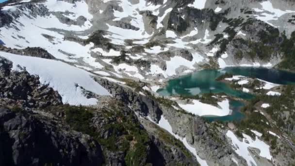 加拿大不列颠哥伦比亚省4K的空中无人机在白雪覆盖的雪山山顶上与灿烂的蓝湖共舞 — 图库视频影像