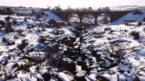 一架无人驾驶飞机与一条河和一辆旧车在美丽的雪地上飞过一座桥的连续画面 — 图库视频影像