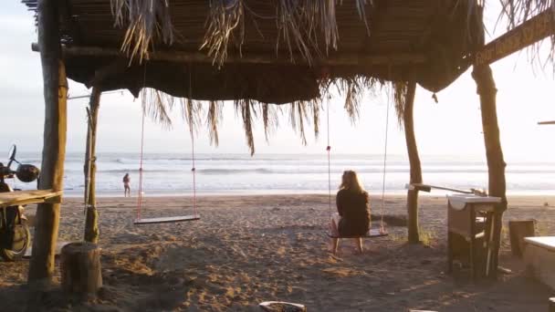 Diapositiva Una Dama Columpio Bajo Una Pérgola Cubierta Hojas Palma — Vídeo de stock