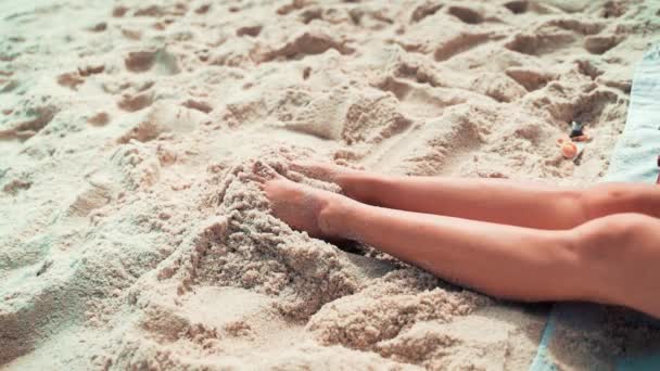 女人在沙滩上伸展双腿 扭动脚趾 以此作为放松的标志 轻松地度过阳光普照的一天 并留有空间 — 图库视频影像