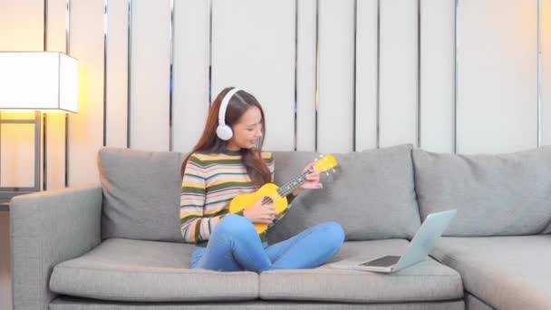 Μια Χαριτωμένη Νεαρή Γυναίκα Κάθεται Σταυροπόδι Έναν Καναπέ Ακούει Μουσική — Αρχείο Βίντεο