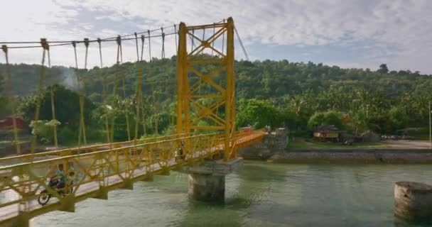 Jembatan Penangguhan Kuning Melintasi Laguna Dangkal Indonesia Dengan Skuter Mengemudi — Stok Video