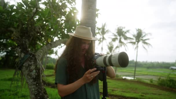 Hip 长发摄影师 带着长镜头在热带拍摄照片 — 图库视频影像