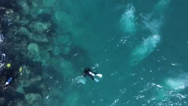 Scuba Dalgıçlarının Okyanus Yüzeyini Baloncuklarla Parçalayan Kayalık Bir Kıyı Şeridini — Stok video