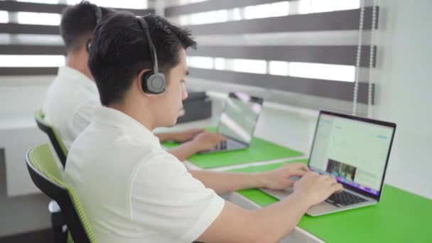 在呼叫中心办公室 客户服务处 Pan Shot的电脑膝上型计算机工作的亚洲男性雇员 — 图库视频影像