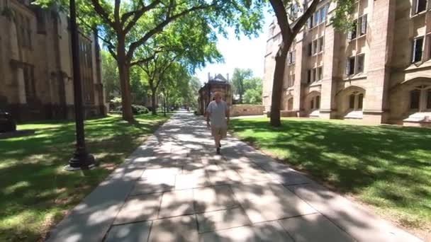キャンパス内を歩く男に続く4Kパン — ストック動画