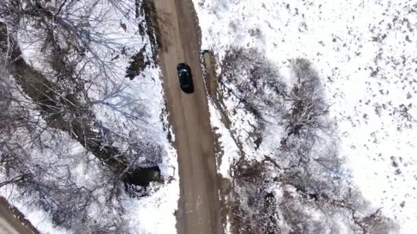 Drohnenaufnahmen Eines Schwarzen Autos Das Eine Schotterstraße Der Verschneiten Wildnis — Stockvideo