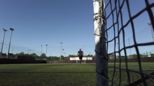 一名业余男性足球运动员在室外人造球场进行长跑训练 并在社交足球比赛前努力健身的低角度镜头 — 图库视频影像