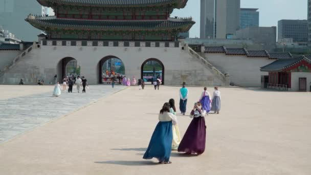 韓服を着た保護面の少女たちが夏に光化門を背に景福宮で写真を撮る — ストック動画