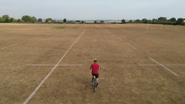 在英国 穿着红衫骑自行车穿越运动场的男人们面临着干旱的环境 无人驾驶飞机跟踪射击 — 图库视频影像