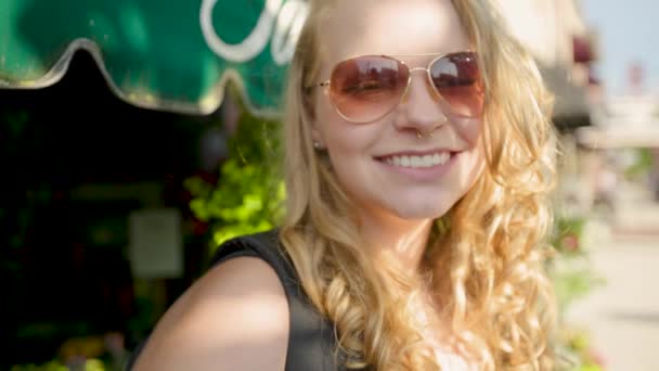 Κορίτσι Προσαρμόζει Γυαλιά Ηλίου Και Χαμόγελα Στην Κάμερα Της Πόλης — Αρχείο Βίντεο