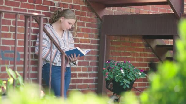 Dziewczyna Odwraca Stronę Czytając Książkę Pod Ścianą Zwolniony Ruch — Wideo stockowe