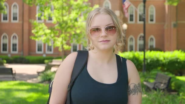 サングラスをかけた女子大生が大学の中に立っている スローモーションで撃たれた — ストック動画
